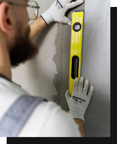 Mann, der eine gelbe Wasserwage gegen eine Wand hält.